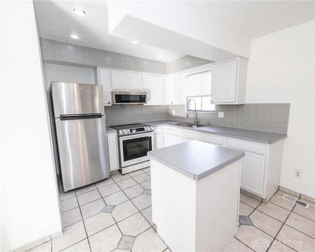 kitchen with white cabinetry, sink, a center island, light tile patterned floors, and appliances with stainless steel finishes