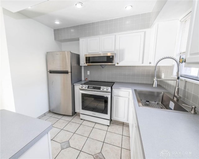 kitchen featuring sink, appliances with stainless steel finishes, tasteful backsplash, light tile patterned flooring, and white cabinetry