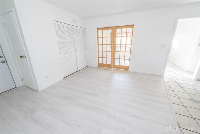 unfurnished bedroom featuring a closet, light hardwood / wood-style flooring, and french doors