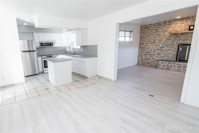 kitchen featuring appliances with stainless steel finishes, a center island, light hardwood / wood-style floors, and white cabinetry