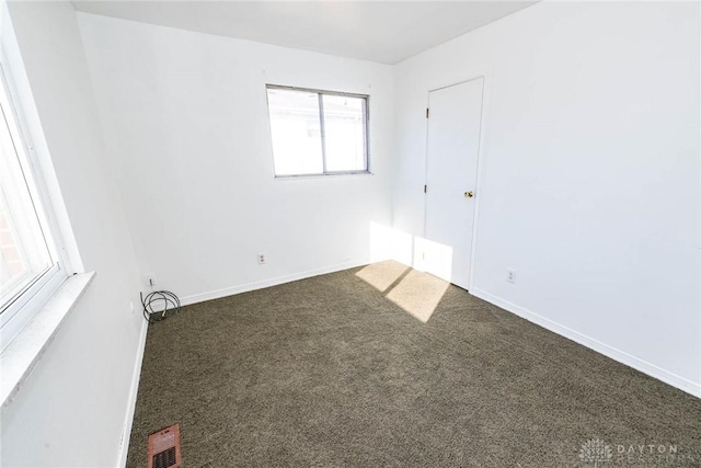 unfurnished room featuring dark carpet