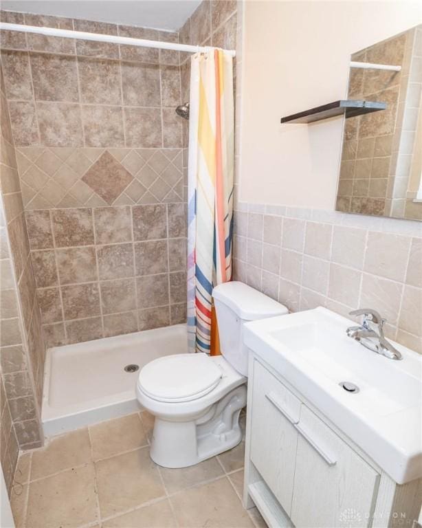 bathroom featuring a shower with curtain, tile patterned flooring, toilet, vanity, and tile walls