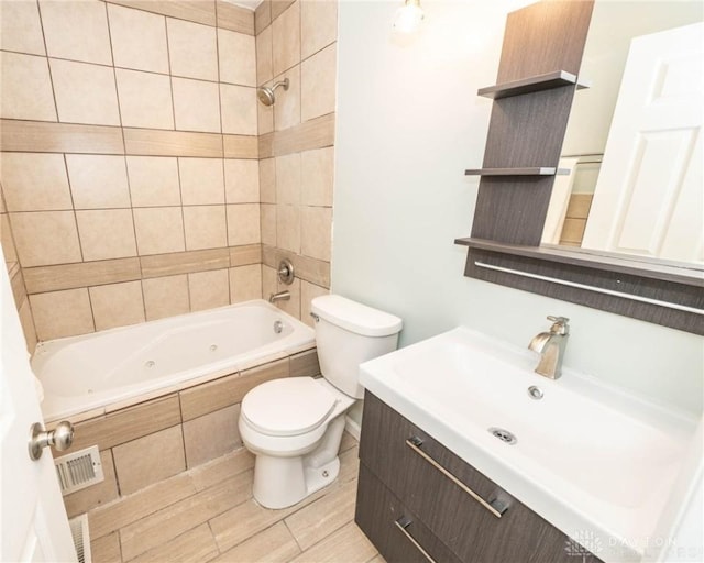 full bathroom featuring vanity, tiled shower / bath combo, and toilet