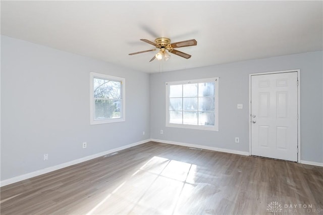 unfurnished room with visible vents, baseboards, a ceiling fan, and wood finished floors