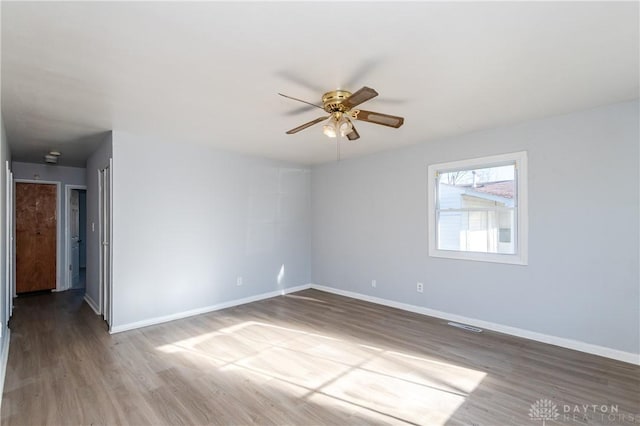 empty room with visible vents, baseboards, ceiling fan, and wood finished floors