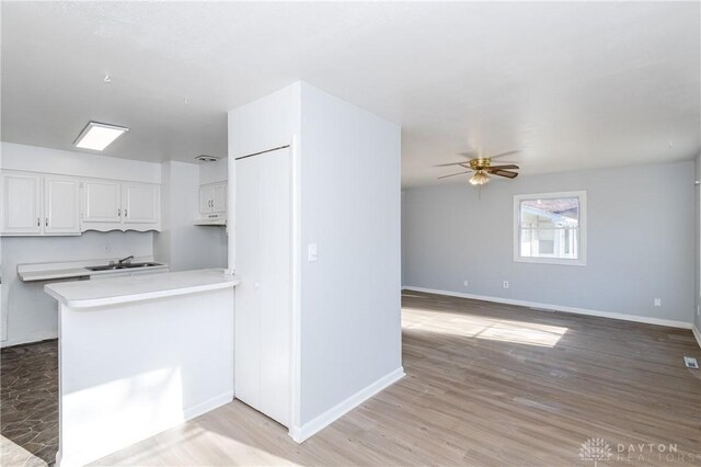 kitchen with ceiling fan, white cabinetry, sink, and kitchen peninsula