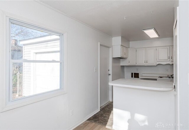 kitchen with white cabinets, kitchen peninsula, sink, and hardwood / wood-style flooring