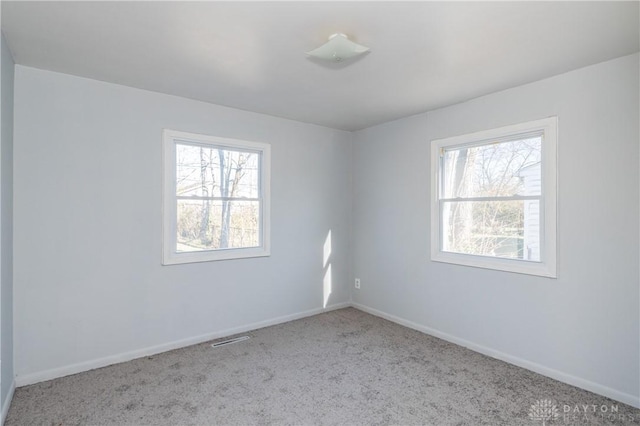 carpeted spare room with visible vents and baseboards