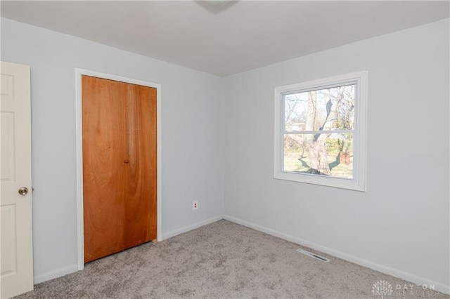 unfurnished bedroom featuring carpet flooring, baseboards, visible vents, and a closet