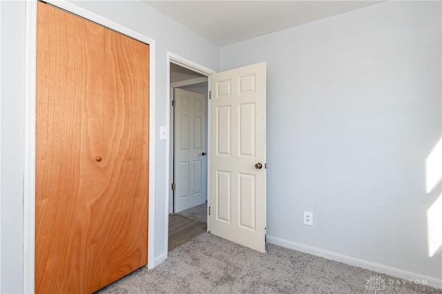 unfurnished bedroom featuring a closet, light colored carpet, and baseboards