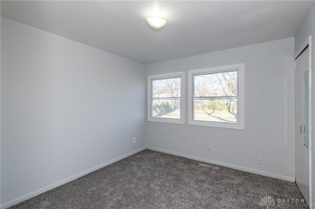 spare room with dark colored carpet