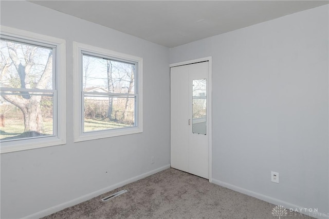 empty room featuring carpet flooring, baseboards, and visible vents
