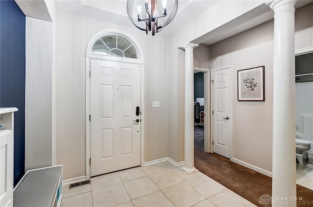 entrance foyer with a chandelier, light tile patterned floors, and ornate columns