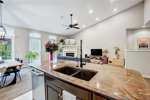 kitchen featuring sink, hanging light fixtures, stainless steel dishwasher, ceiling fan, and light stone countertops