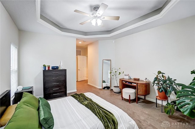 carpeted bedroom with ceiling fan and a tray ceiling