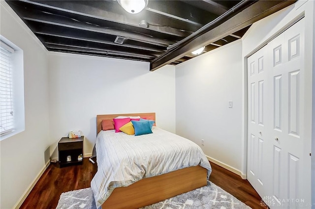 bedroom featuring beam ceiling, multiple windows, and dark hardwood / wood-style floors