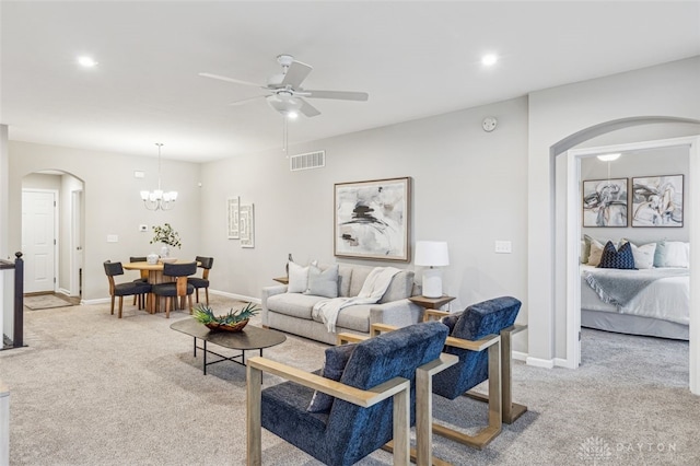 living room featuring ceiling fan with notable chandelier and light carpet