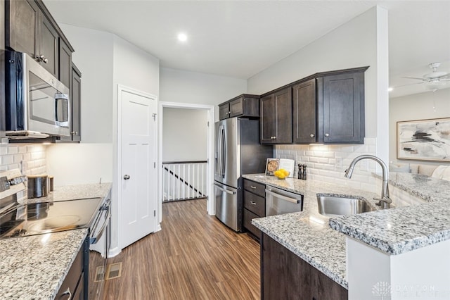 kitchen featuring light stone countertops, appliances with stainless steel finishes, dark hardwood / wood-style flooring, tasteful backsplash, and sink