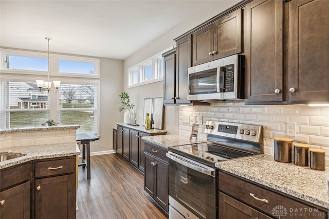 kitchen featuring hanging light fixtures, appliances with stainless steel finishes, a notable chandelier, dark hardwood / wood-style flooring, and dark brown cabinets