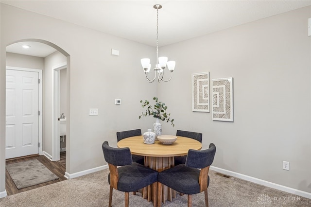 dining room with carpet flooring and a notable chandelier