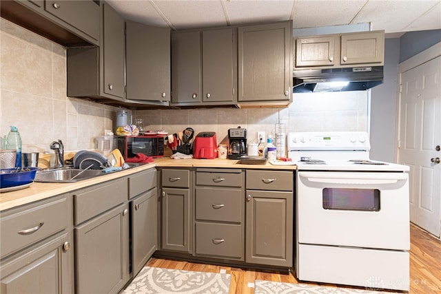 kitchen with gray cabinets, electric stove, tasteful backsplash, sink, and light hardwood / wood-style flooring