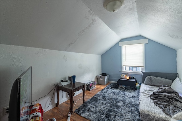 bedroom featuring lofted ceiling, wood-type flooring, and a textured ceiling