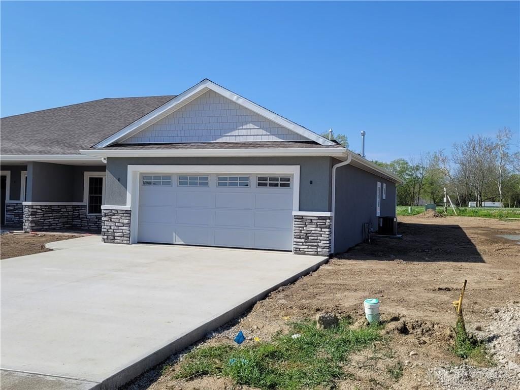 view of property exterior featuring a garage, cooling unit, concrete driveway, and stone siding