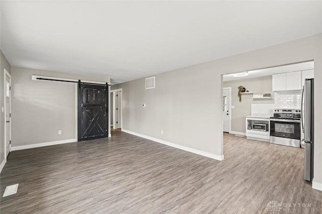 unfurnished living room featuring a barn door and hardwood / wood-style flooring