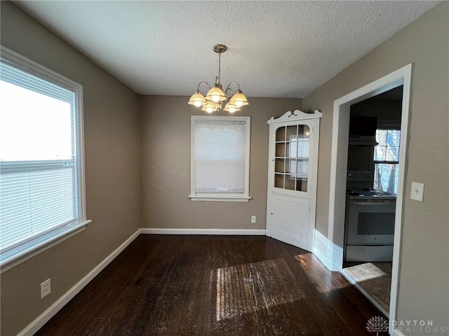 unfurnished dining area with a textured ceiling, dark hardwood / wood-style floors, and an inviting chandelier