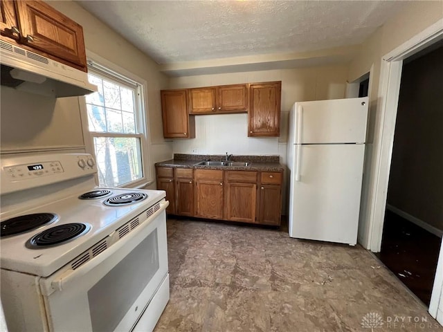 kitchen with a textured ceiling, white appliances, and sink