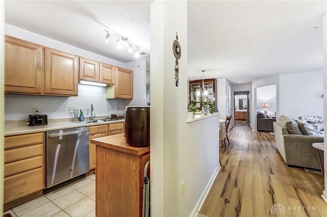 kitchen with pendant lighting, wood counters, sink, stainless steel dishwasher, and light wood-type flooring