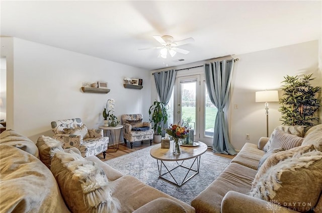 living room featuring ceiling fan, a water view, and hardwood / wood-style flooring