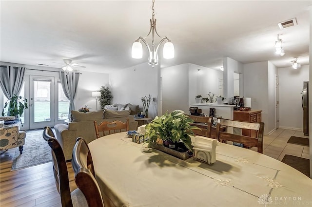 dining space featuring ceiling fan with notable chandelier and light wood-type flooring