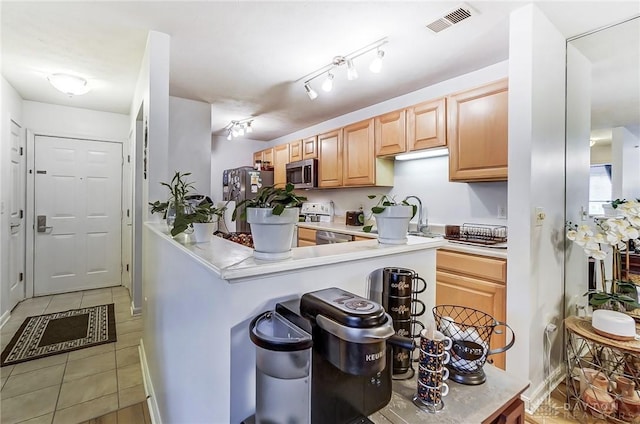 kitchen featuring light tile patterned floors, light brown cabinetry, kitchen peninsula, and appliances with stainless steel finishes