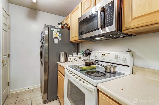 kitchen featuring white range with electric cooktop, light tile patterned floors, and light brown cabinetry