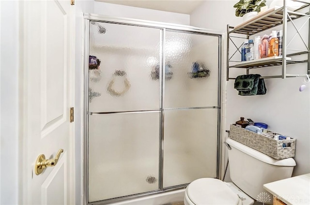 bathroom with vanity, toilet, and a shower with door