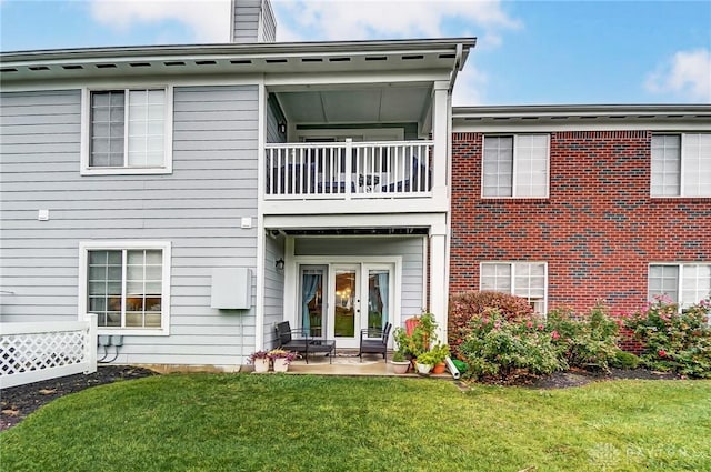 rear view of property with a patio area, a yard, and a balcony