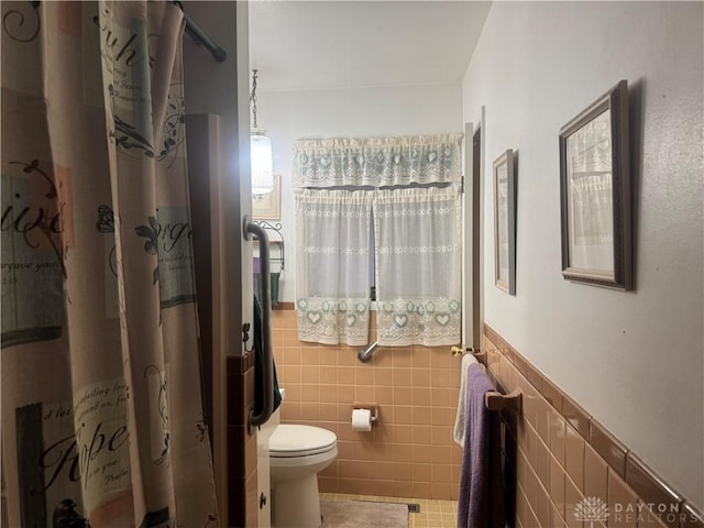 bathroom featuring tile patterned flooring, toilet, tile walls, and walk in shower