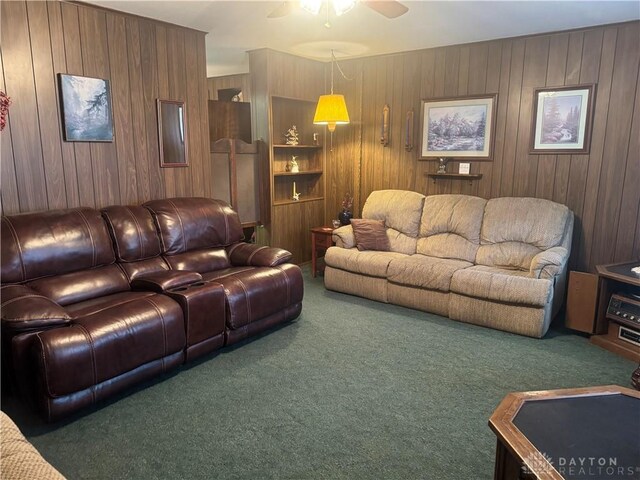 living room featuring ceiling fan, wood walls, and dark colored carpet