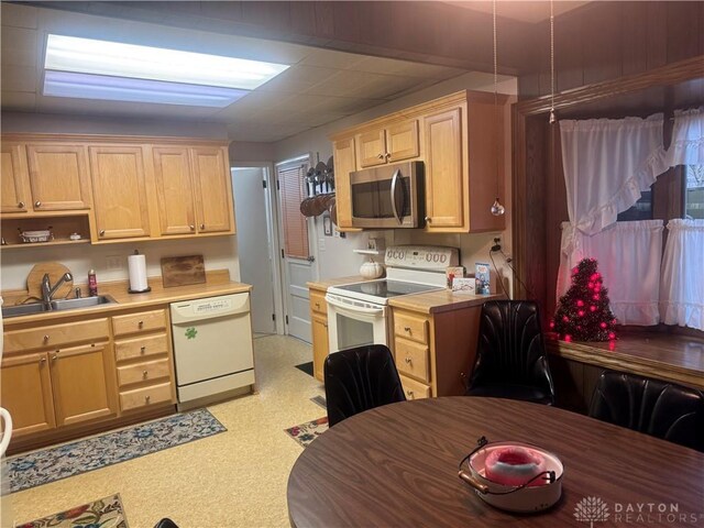 kitchen featuring light brown cabinetry, sink, and white appliances