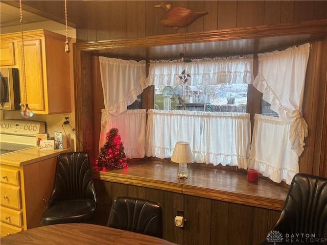 kitchen with pendant lighting, wood walls, and range with electric cooktop