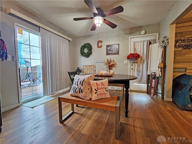 dining room with hardwood / wood-style floors, ceiling fan, and wooden walls