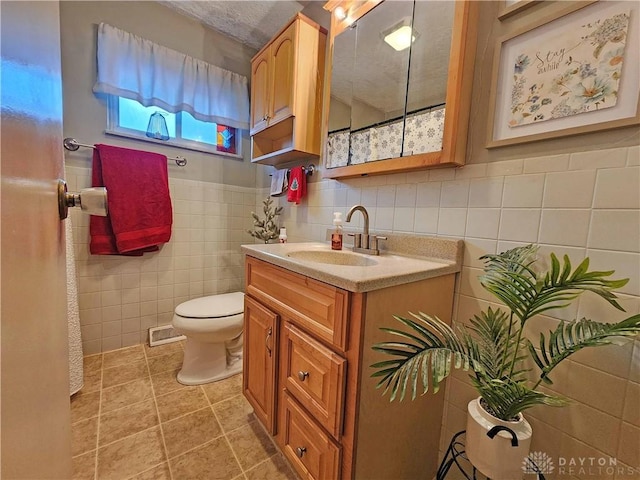 bathroom with tile patterned floors, vanity, toilet, and tile walls