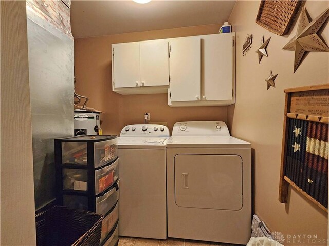 washroom with washer and clothes dryer, light tile patterned flooring, and cabinets