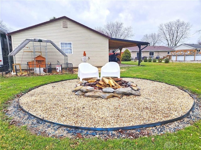 back of property featuring a fire pit and a yard