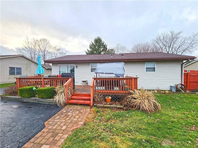 back of house featuring a lawn and a wooden deck