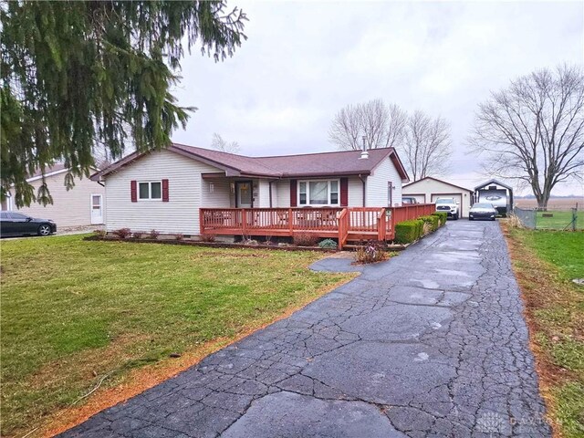 ranch-style home featuring a garage, a deck, an outbuilding, and a front lawn