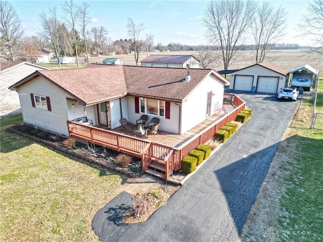 view of front of property featuring a garage, a wooden deck, an outbuilding, and a front lawn