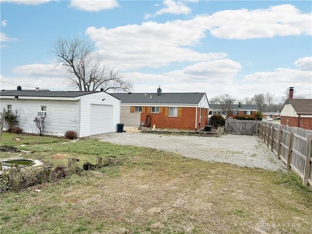 back of property with a garage and a lawn