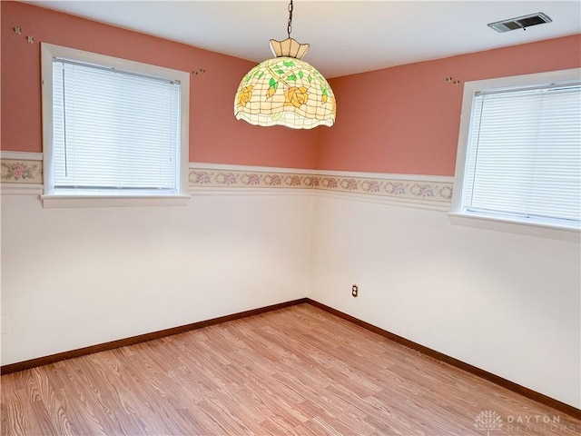 spare room featuring a wealth of natural light and light hardwood / wood-style flooring